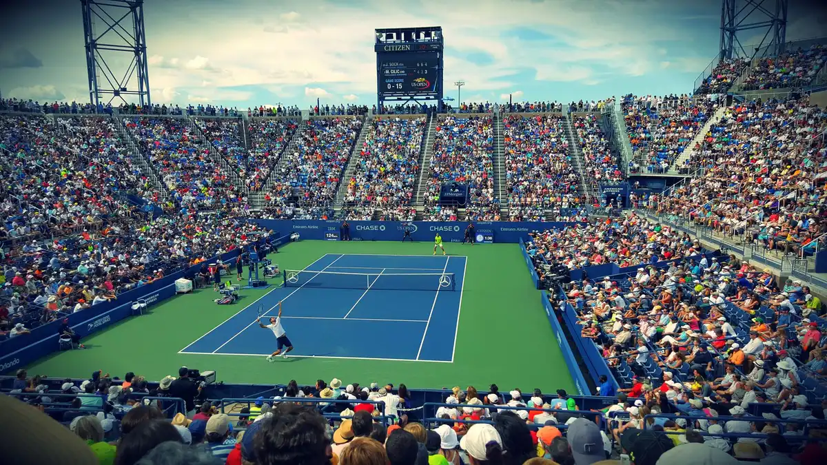 A professional tennis player walking toward the net after a match, crowd visible in the background, arena lighting, composed expression