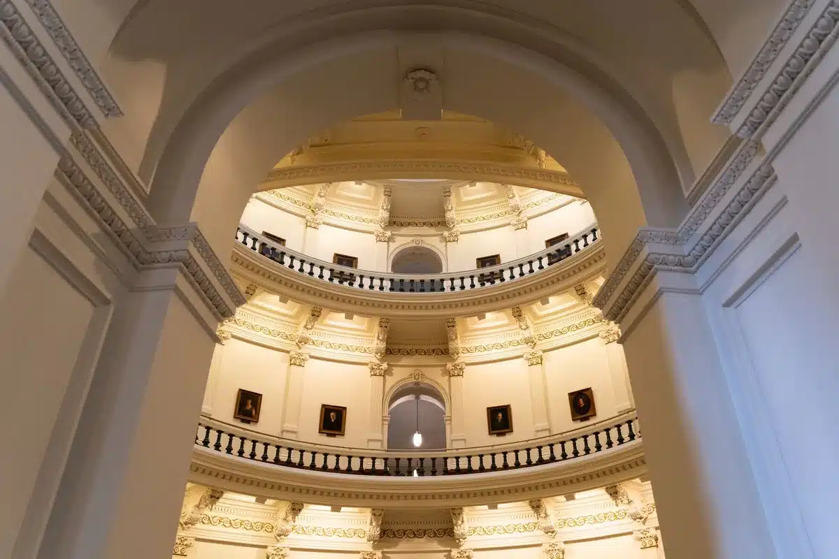 An empty Capitol building hallway at dusk, with muted blue and gold light reflecting off marble floors, a single American flag visible in soft focus