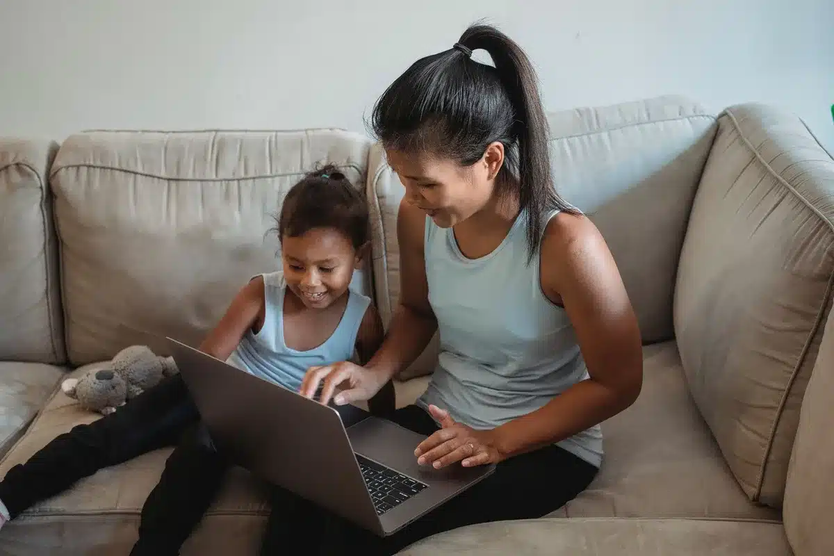 A parent and child sitting at a table with a smartphone between them, the parent gesturing toward the screen with concern, morning light through a window
