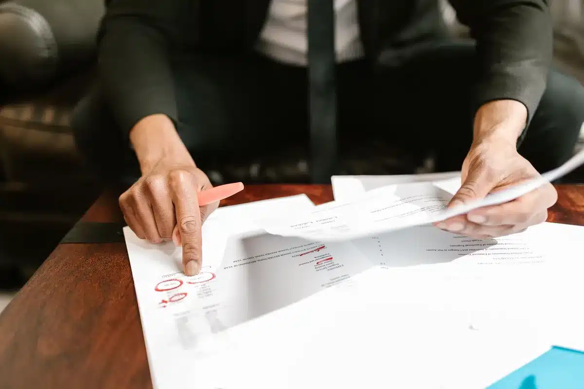 Congressional staff reviewing budget documents at a conference table, papers spread across the surface, serious focus, fluorescent office lighting