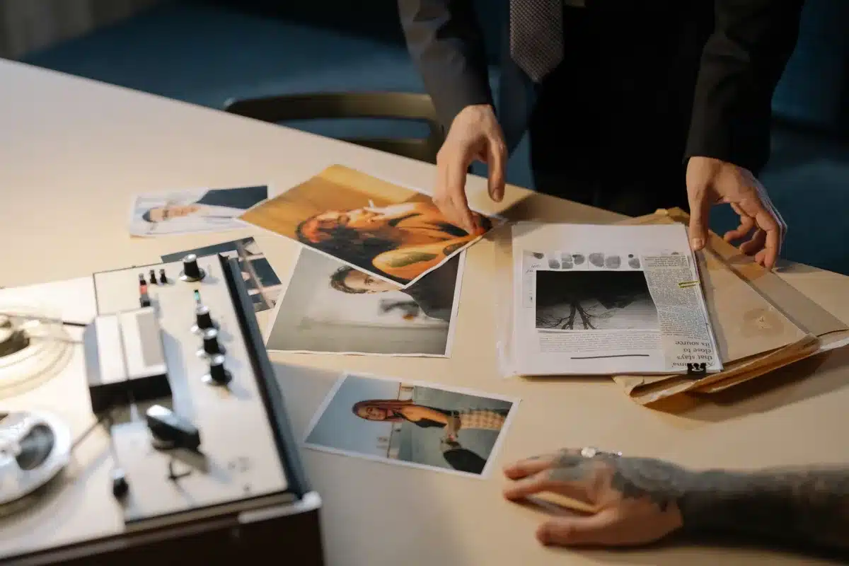 Award-winning journalist at a desk reviewing documents and notes, surrounded by research materials and news archives, concentrated expression suggesting investigative work