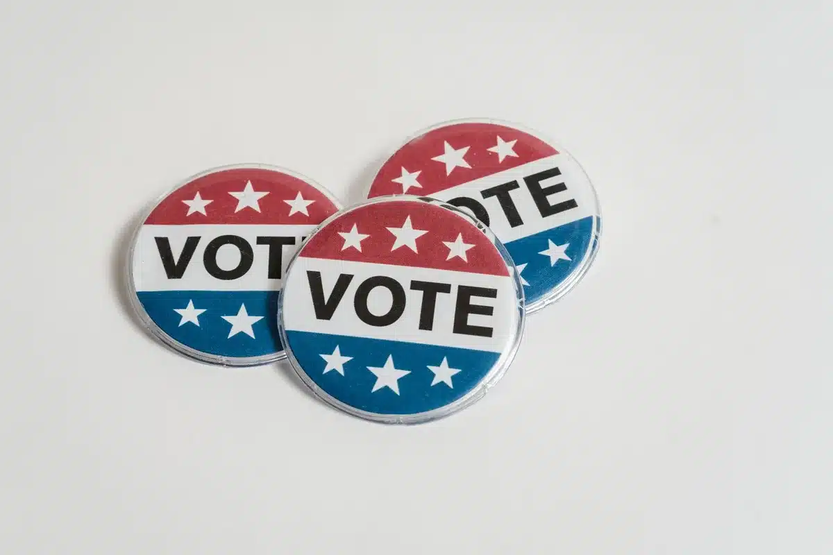 A close-up of campaign literature and voting materials spread on a desk, with Ohio state symbols visible, natural daylight on paper, subtle depth of field