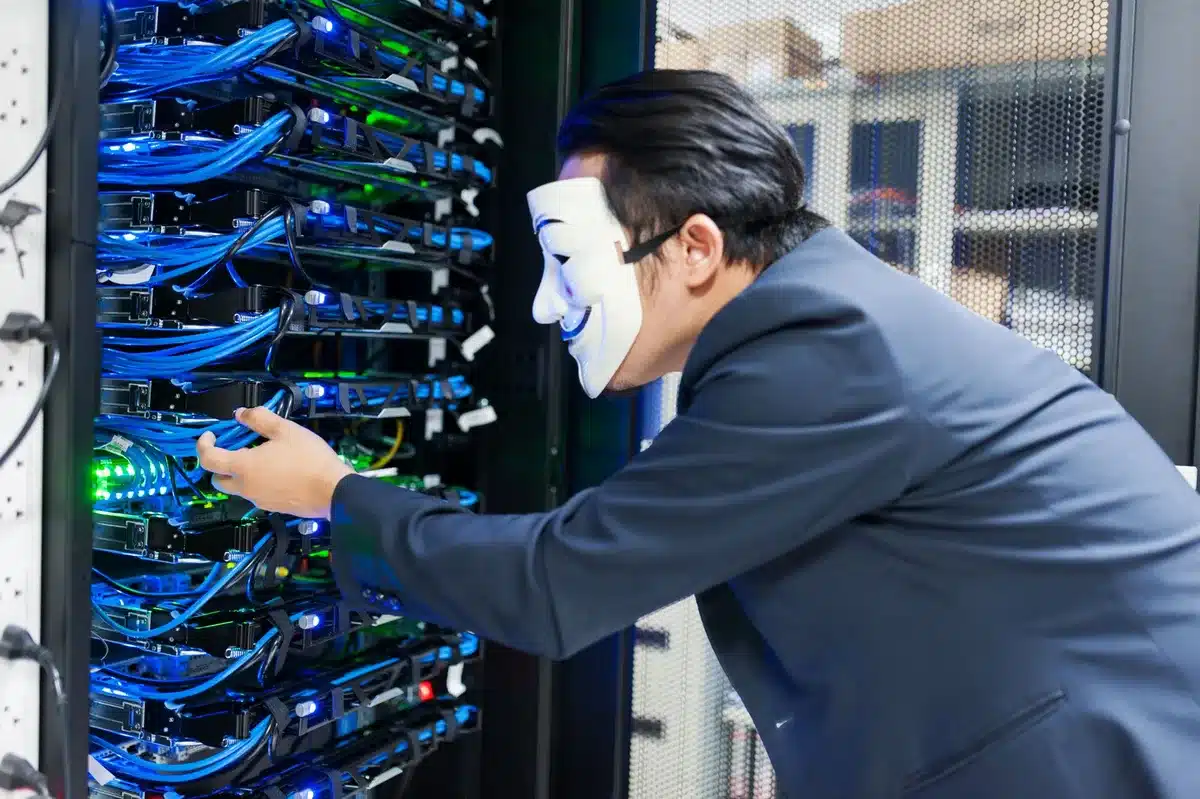 A data center server rack bathed in cool blue light, rows of metal chassis stacked vertically with glowing status indicators and cable management visible, conveying industrial scale and technological intensity.