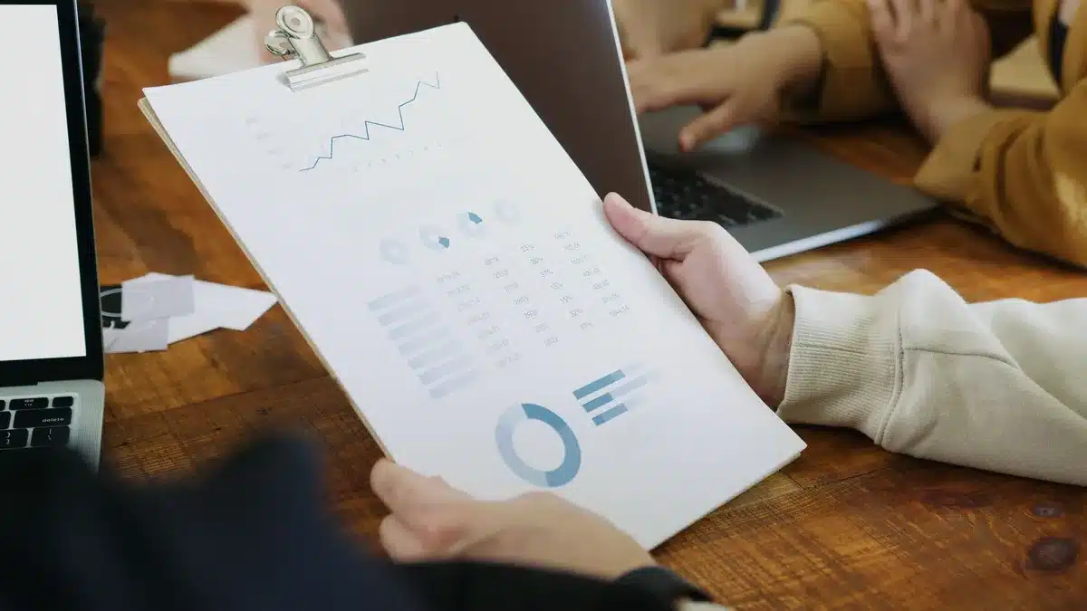 Close-up of a laptop keyboard with glowing keys, a financial dashboard visible on screen showing candlestick charts and earnings data, shallow depth of field