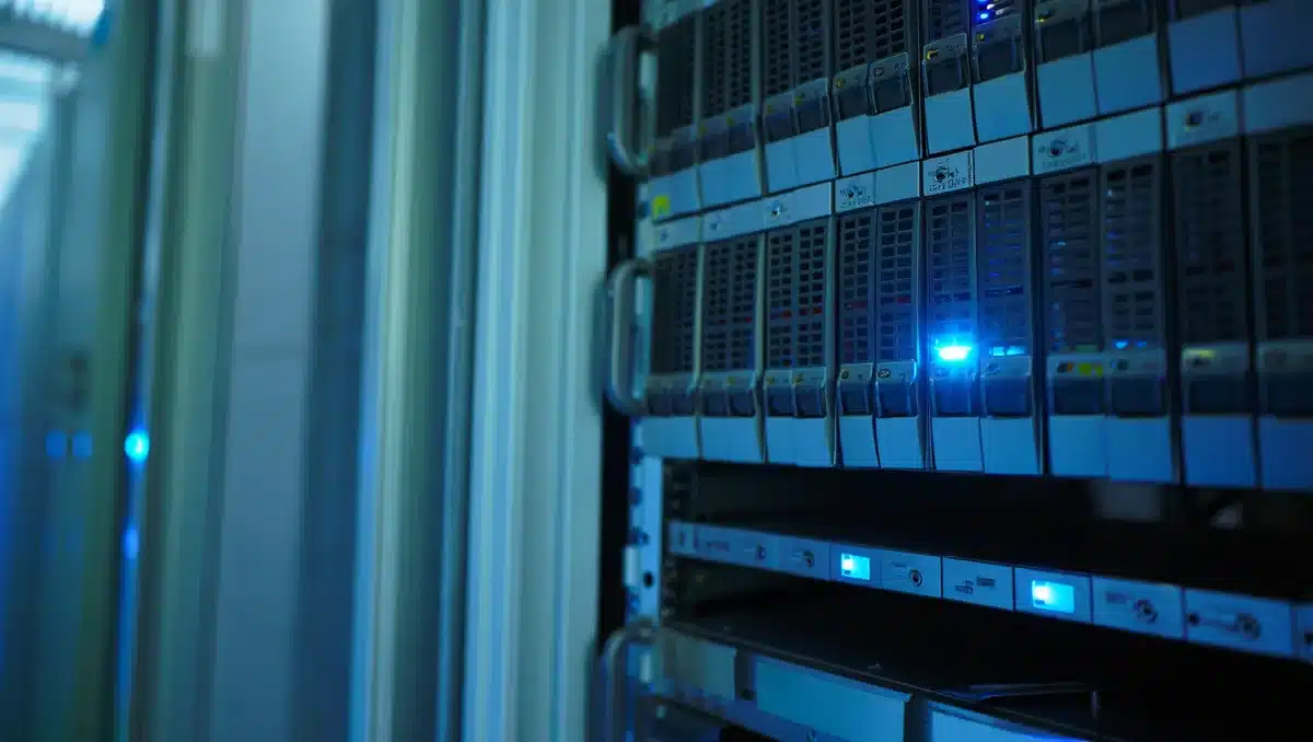 Data center servers with glowing LED indicators, stacked in rows under cool blue lighting, rows of equipment stretching into depth | data center hardware infrastructure