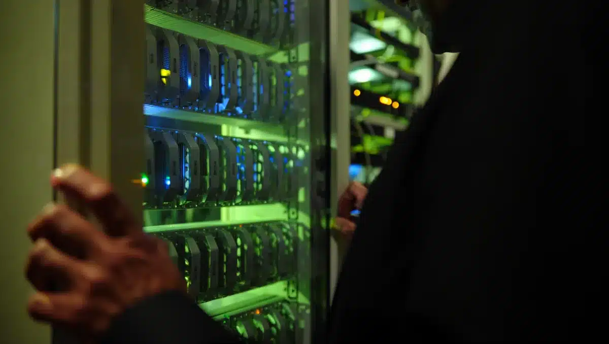Glowing computer server racks in a dimly lit data center, blue and green indicator lights reflecting off metal surfaces, rows of equipment stretching into shadow | data center storage servers