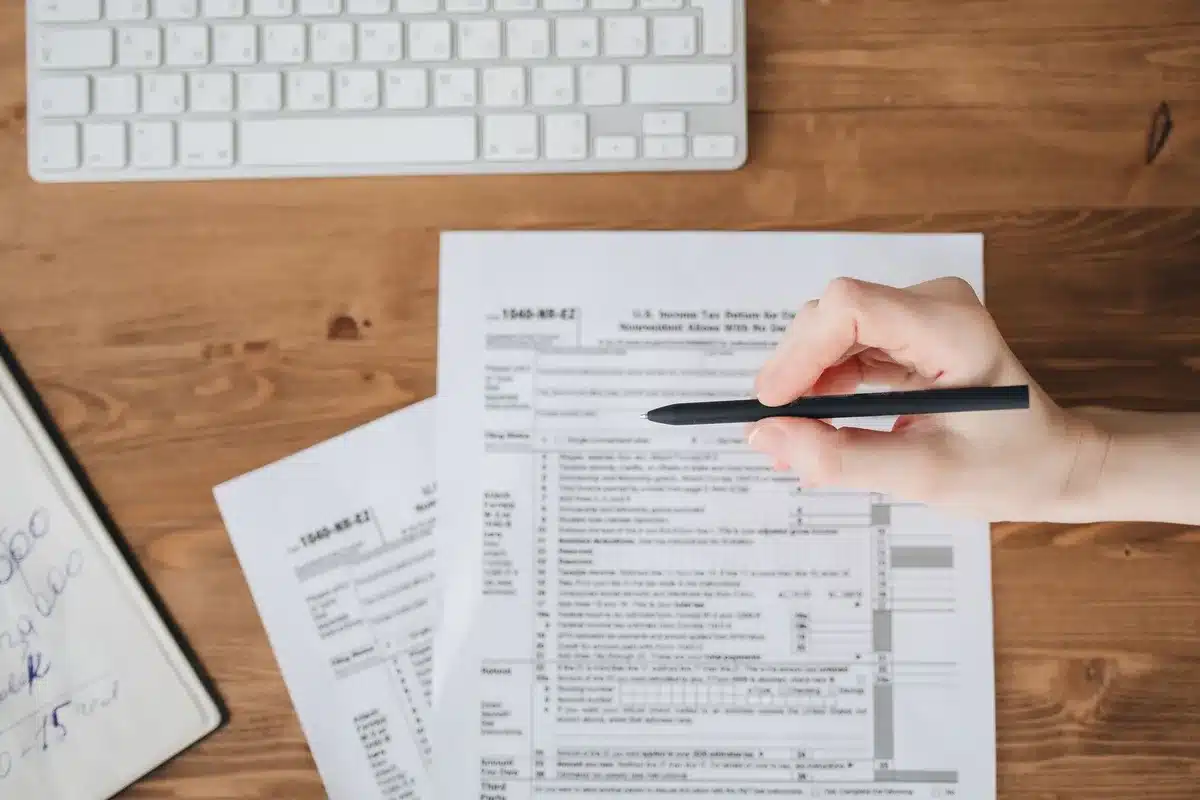 A retiree reviewing financial documents at a desk with a calculator and bills spread out
