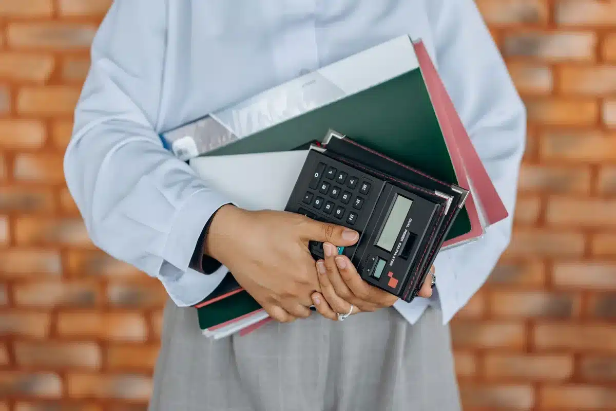 A retiree reviewing financial documents at a desk, papers and calculator visible, morning sunlight through a window, contemplative focus