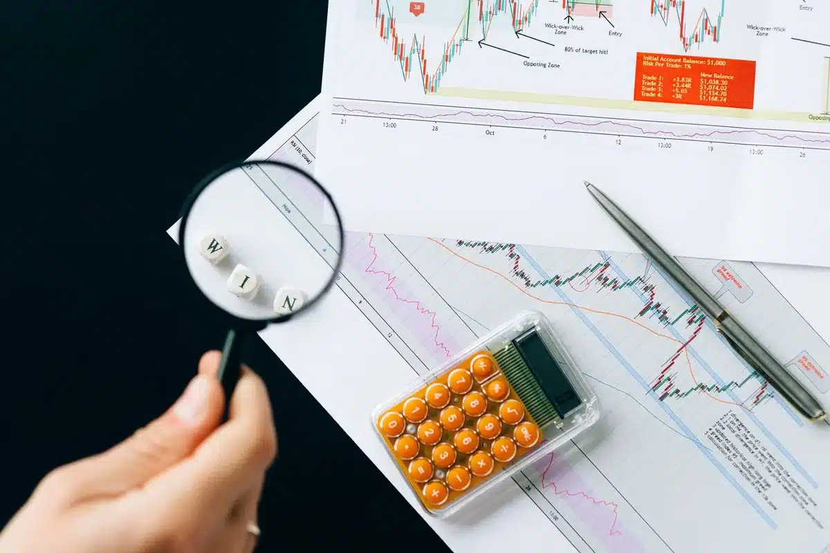 A computer screen displaying an inflation chart with upward and downward trend lines, a calculator and notepad beside it, suggesting financial analysis.