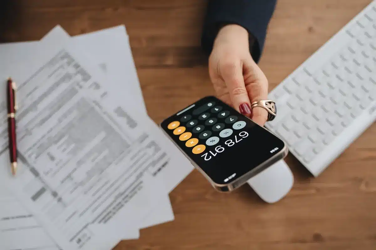A calculator displaying Social Security benefit figures with financial documents and charts showing percentage increases