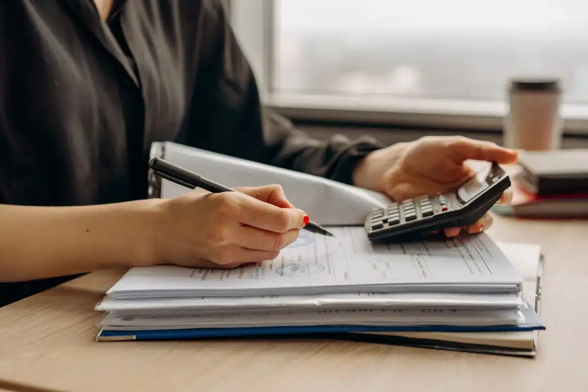 A calculator and financial documents showing benefit amounts and percentage increases, arranged on a desk with a pen, representing retirement income planning