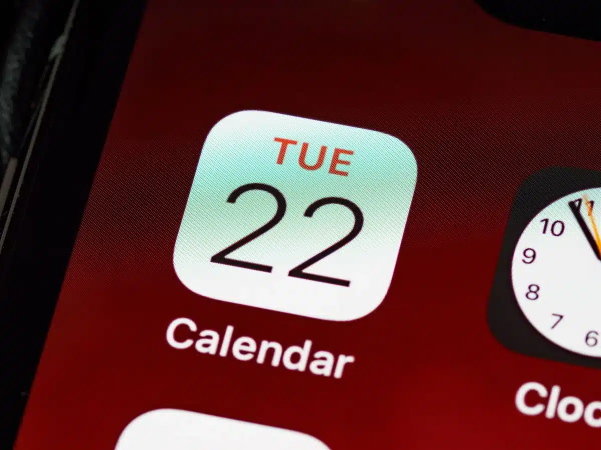 Close-up of a calendar page showing October 14 circled in red, a pen lying across the date, soft focus background of a desk with financial papers