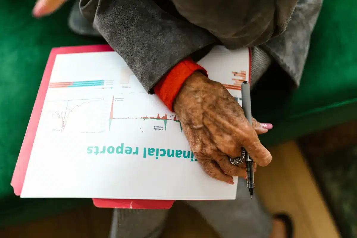 Retirees reviewing financial documents at a table, reading glasses, papers with numbers, morning light