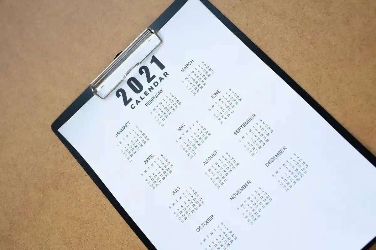A calendar page highlighting October 14, 2026, in a home office setting with reading glasses and a notepad nearby, soft natural light from a window, waiting