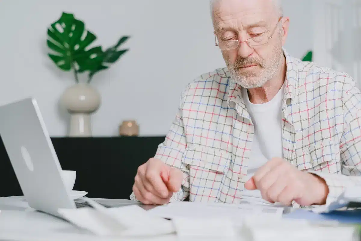 A retiree's monthly benefit statement showing adjusted payment amounts, with pension paperwork and reading glasses on a desk, representing the financial impact of policy changes on retirement income security.
