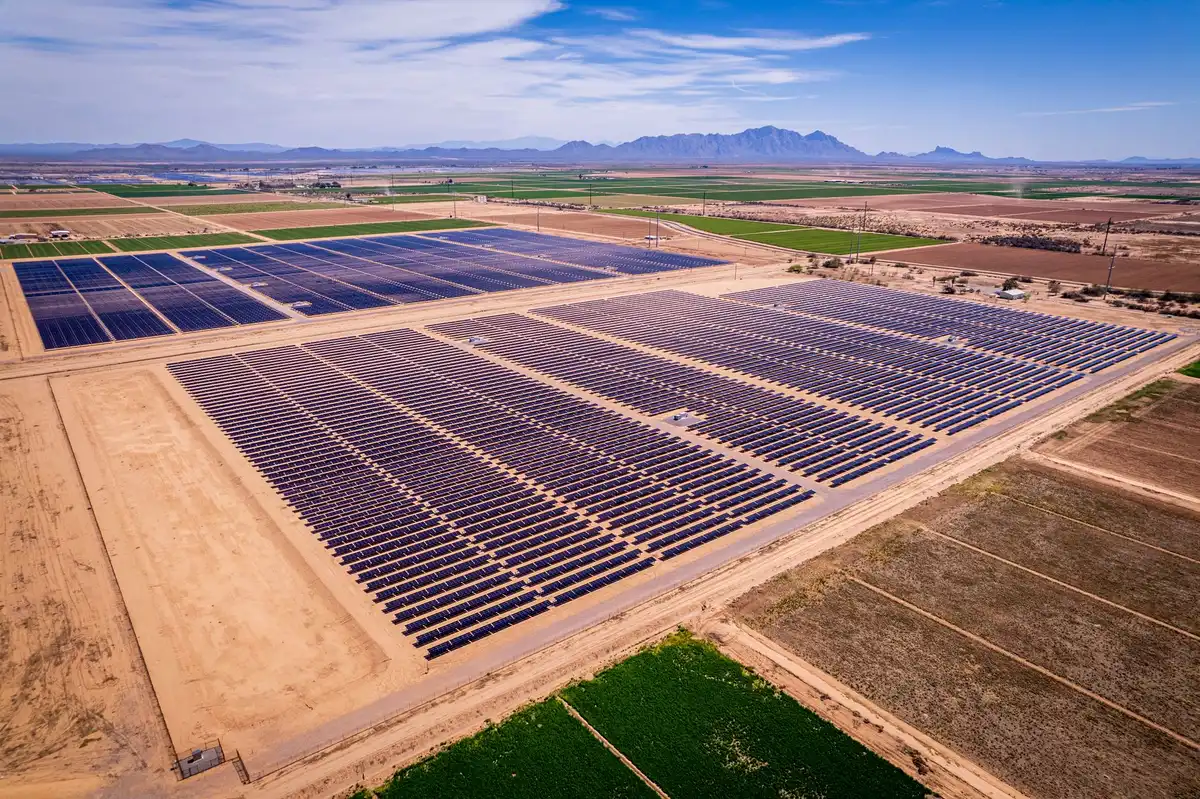 A glowing solar panel array stretching across a landscape under bright sunlight, with rows of photovoltaic cells reflecting light, representing the record-breaking capacity driving solar's rise.