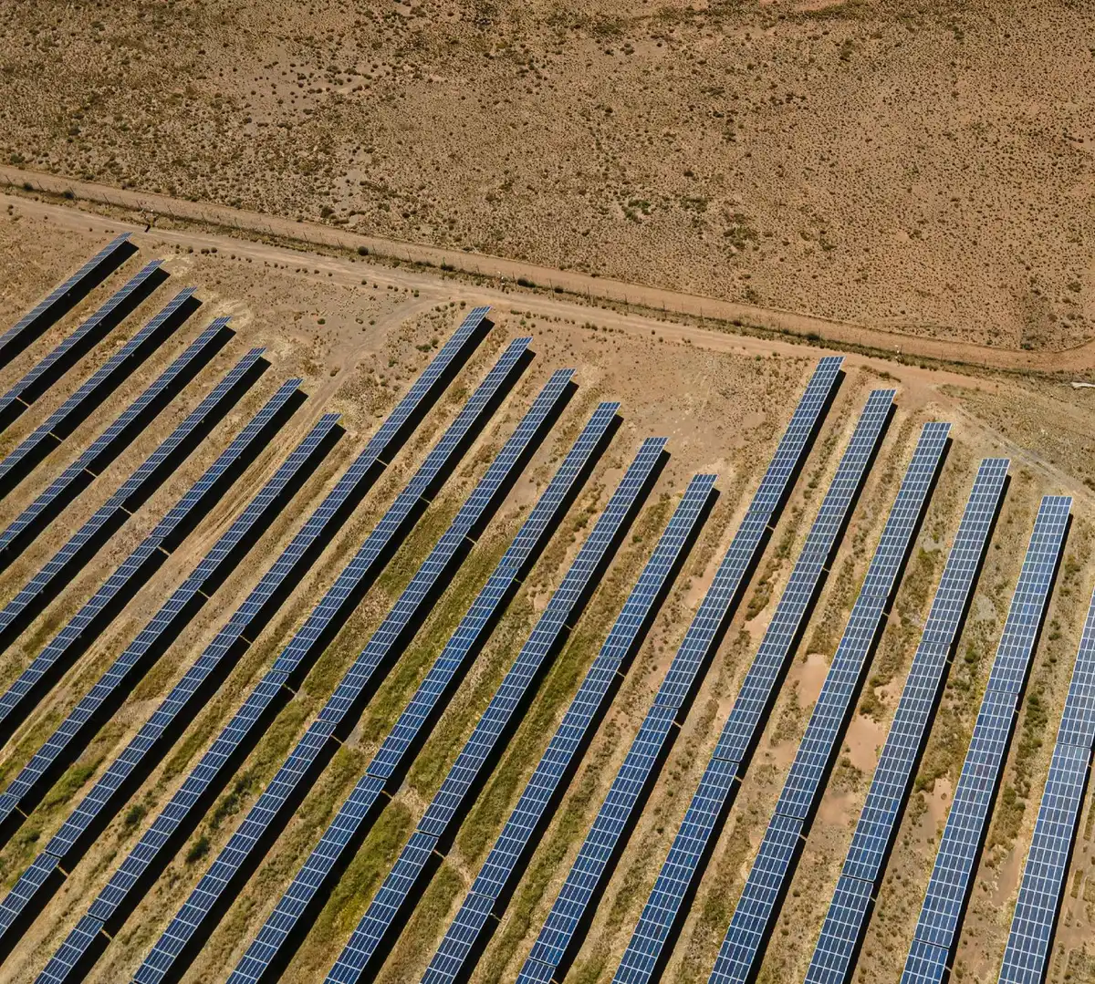 A utility-scale solar farm under clear skies with modern inverters and equipment visible, showing the infrastructure supporting grid-scale solar deployment and capacity growth.