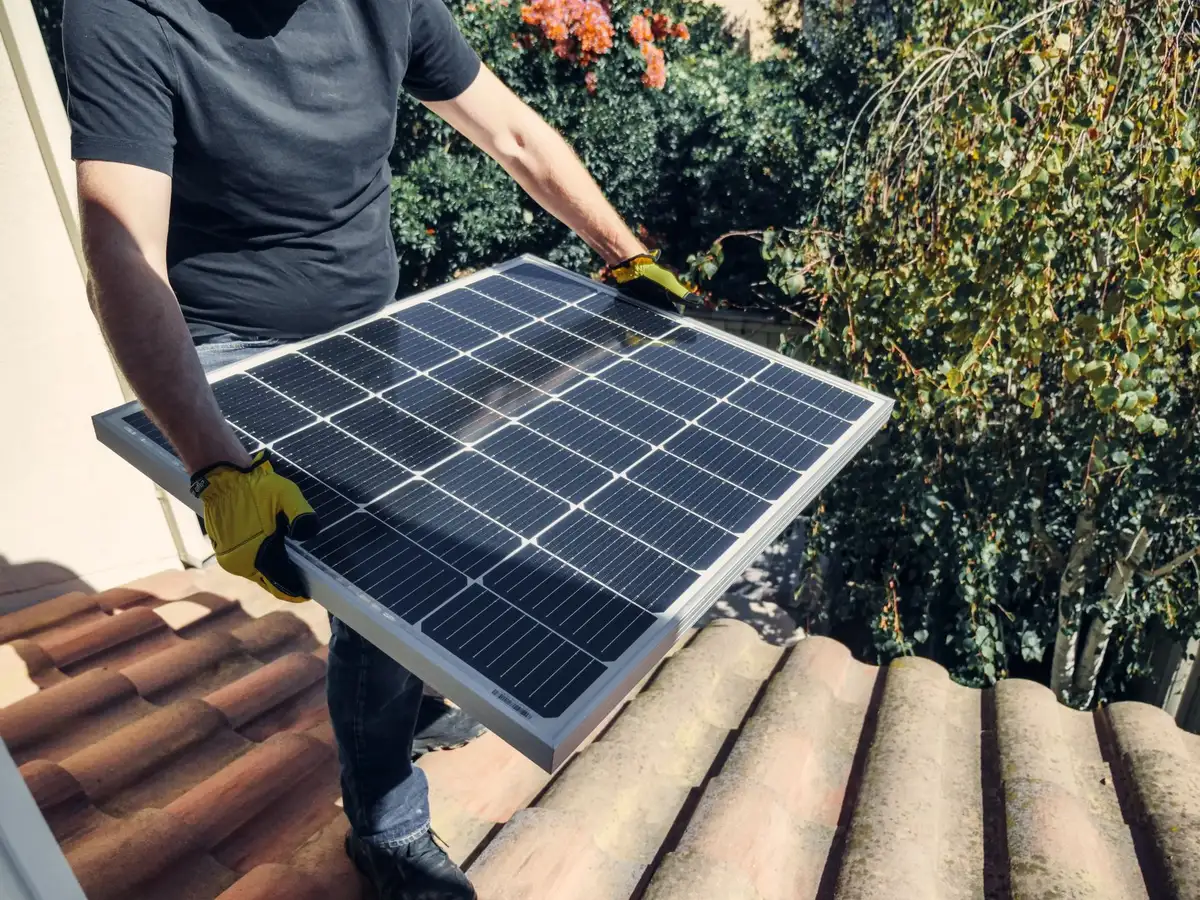 A homeowner's rooftop catching morning sunlight, with solar panels installed and glistening, the surrounding residential neighborhood visible in soft focus below, symbolizing renewable energy adoption and long-term savings.
