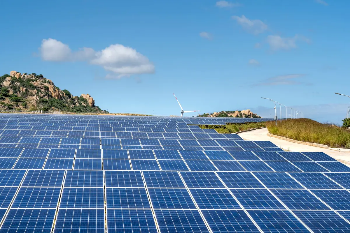 Industrial solar panel manufacturing facility with rows of completed panels ready for shipment, bright warehouse lighting