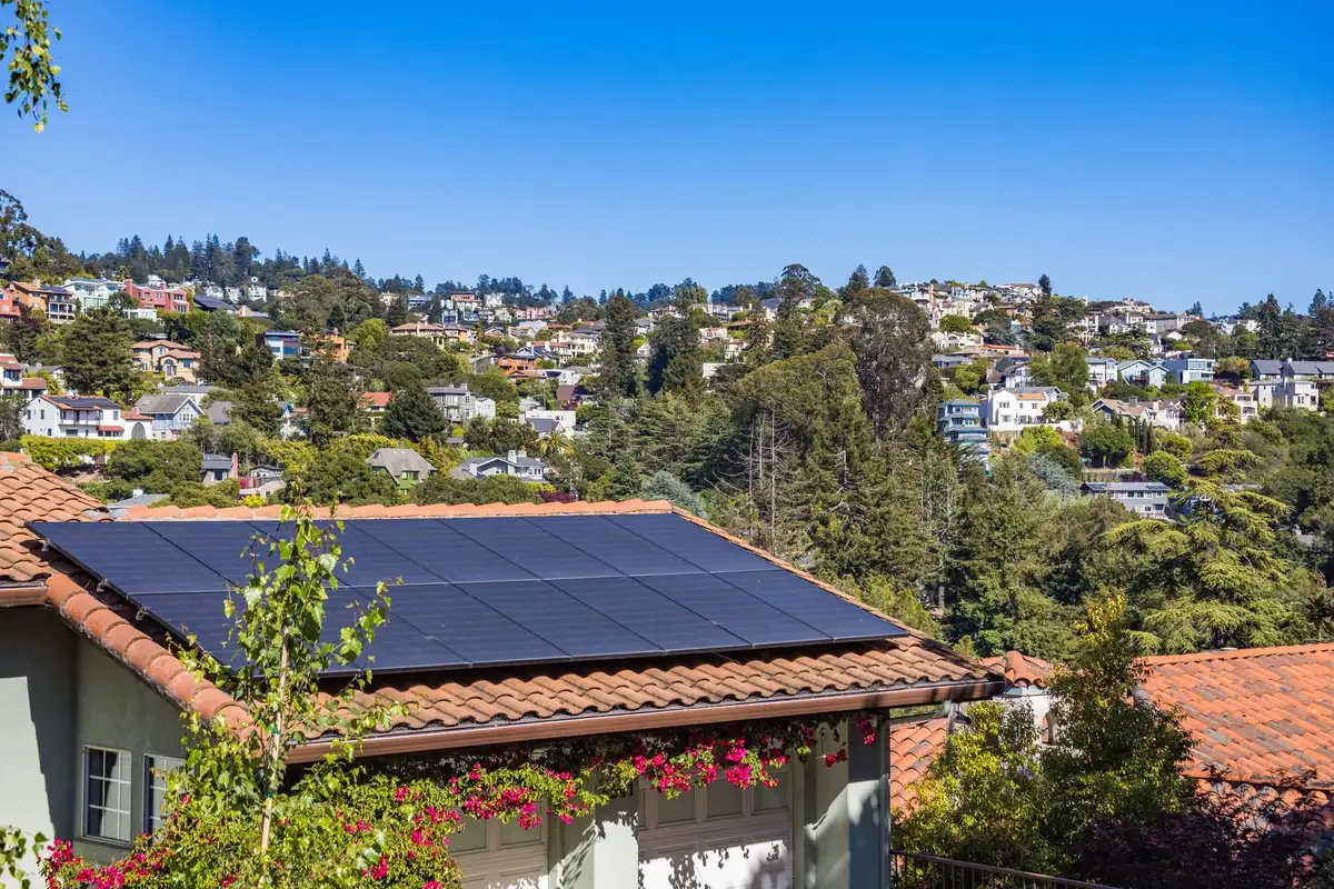Modern rooftop solar panels installed on residential homes with blue sky visible, showing suburban neighborhood landscape