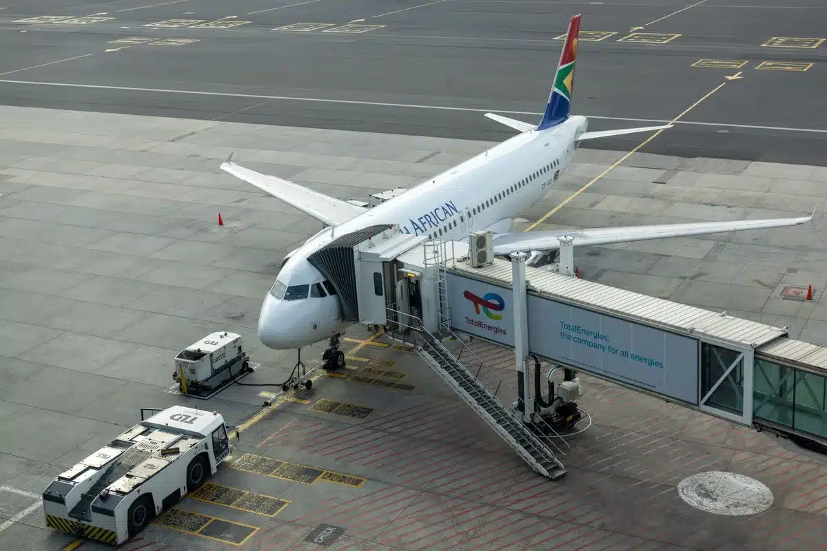 Flight attendants in uniform preparing a Boeing 737 cabin, checking overhead bins and organizing boarding materials, focused expressions showing preparation and efficiency.