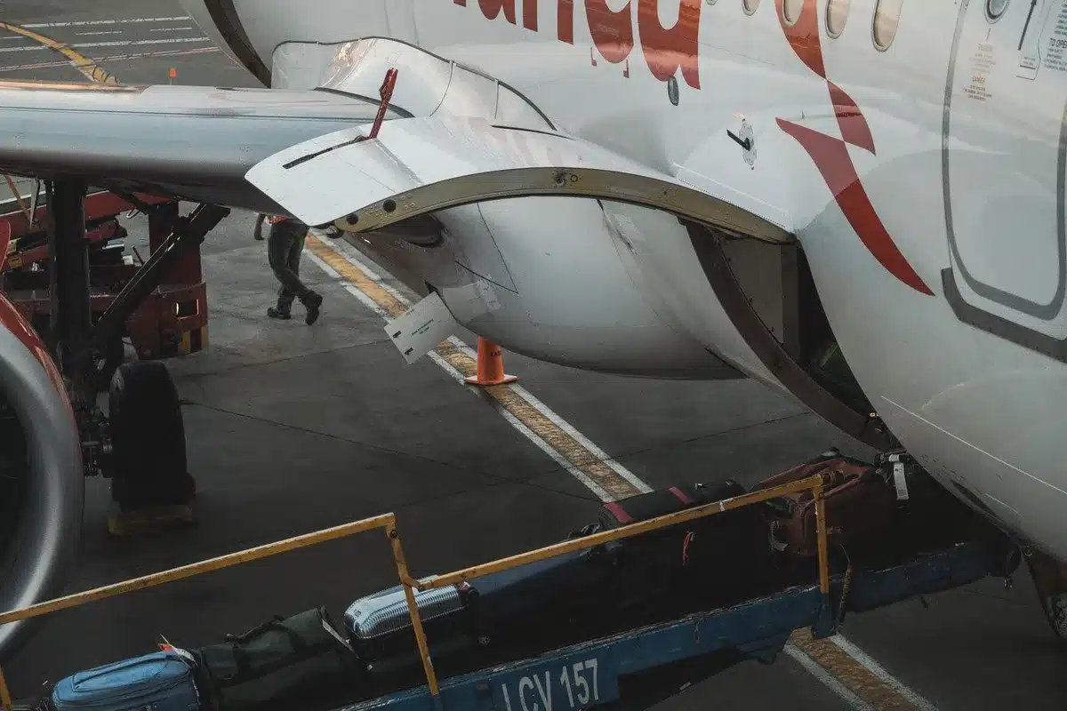 Overhead bins in a commercial aircraft interior packed with carry-on luggage, showing overflow and crowding, illustrating the space constraints passengers face.