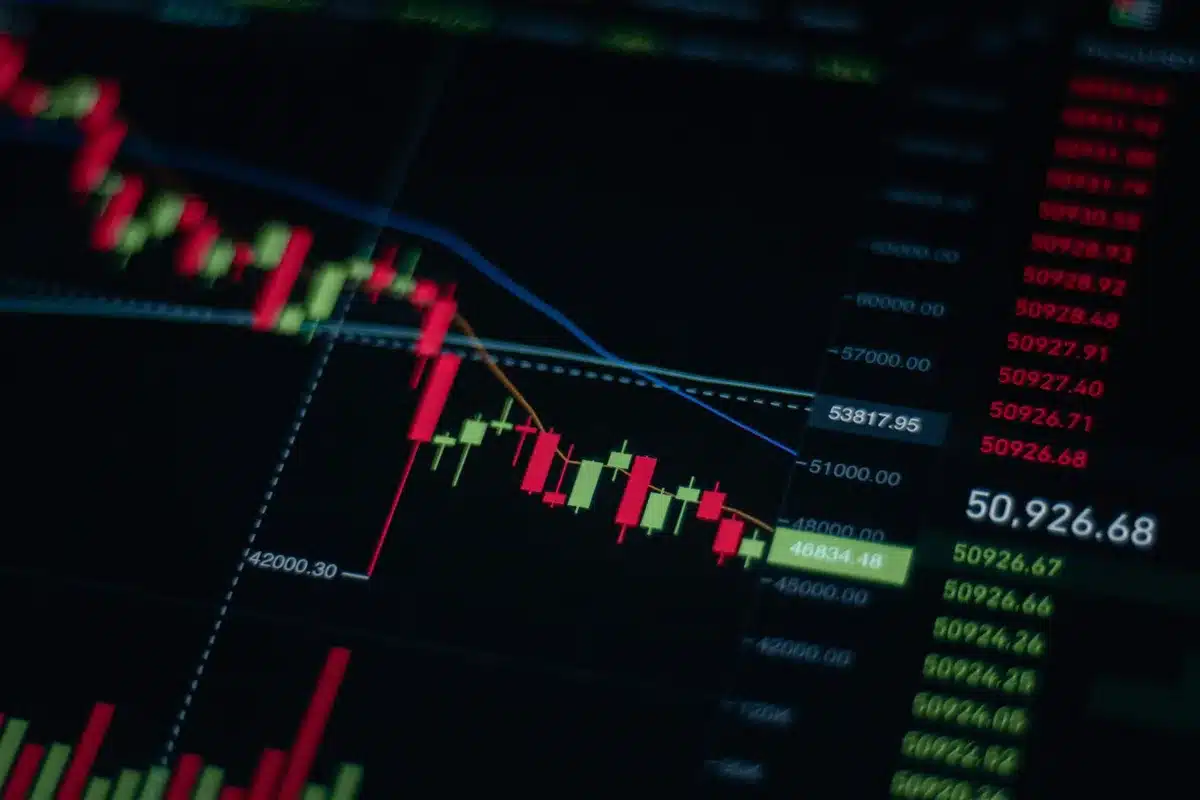 Glowing stock ticker showing green numbers and upward-trending line graph, dark background with soft light reflection