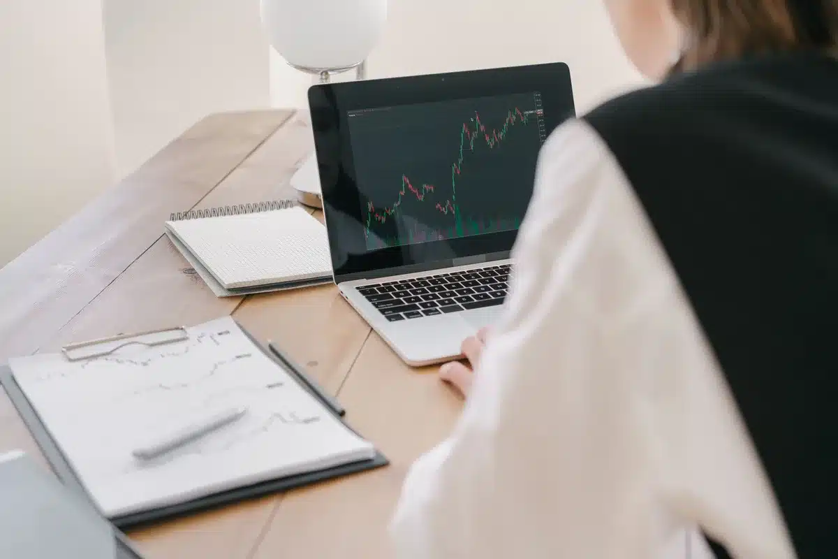 A stock market trading floor with screens displaying green gains, traders in focus, early morning light streaming through windows