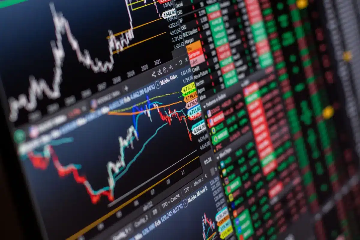 Stock market floor traders monitoring screens and price tickers, focused expressions as indices climb, floor activity under bright lights