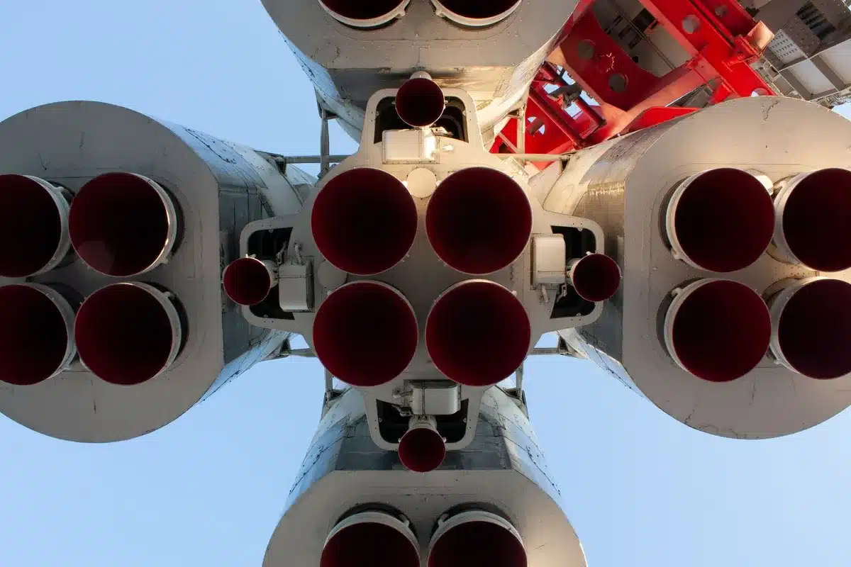 A Falcon 9 first-stage booster descending toward a landing zone, its engines ignited for the landing burn, with landing legs extending against the night sky