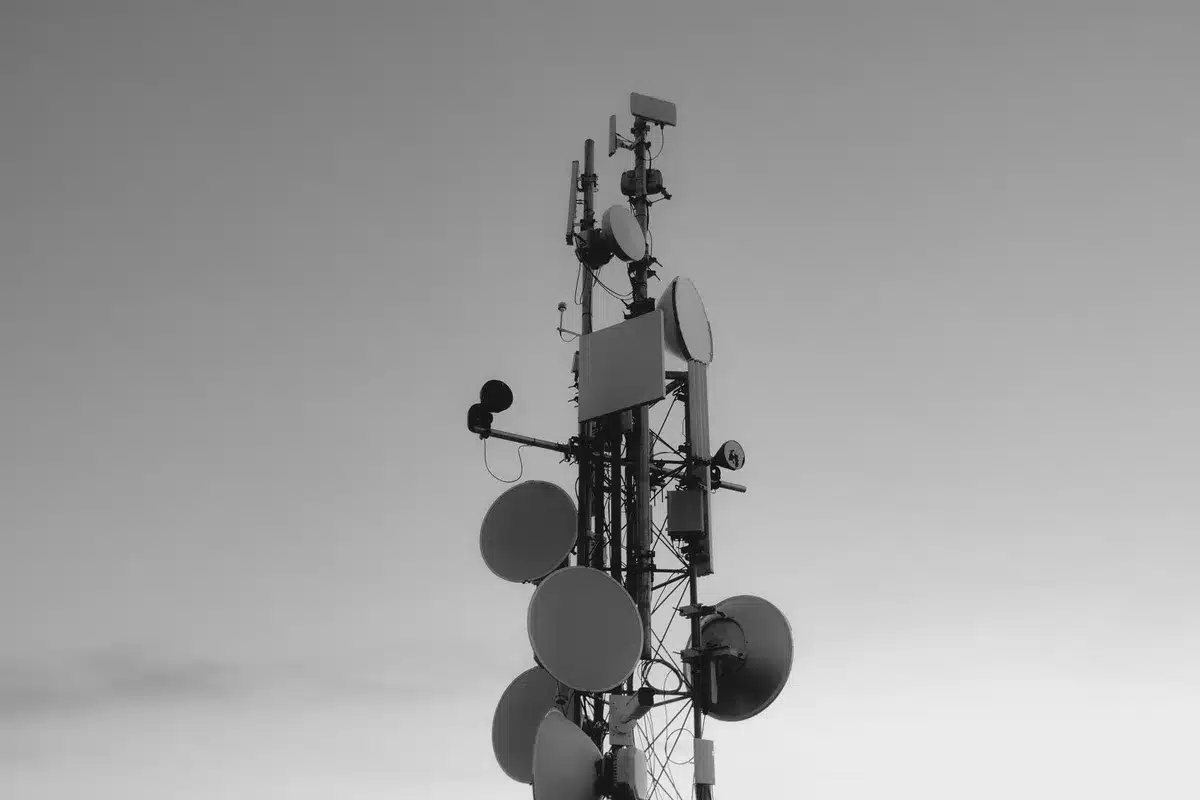 A split-screen visualization showing a satellite in low Earth orbit on the left, transmitting signal waves downward to a smartphone on the right, with a global map background showing coverage zones in blue.