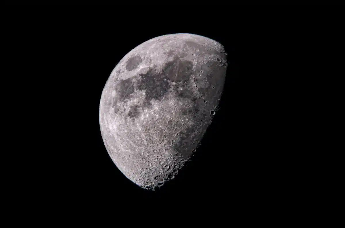 A detailed view of the lunar surface showing multiple ancient impact craters of varying sizes, with mountains and ridges casting shadows, illustrating the Moon's long history of celestial collisions.