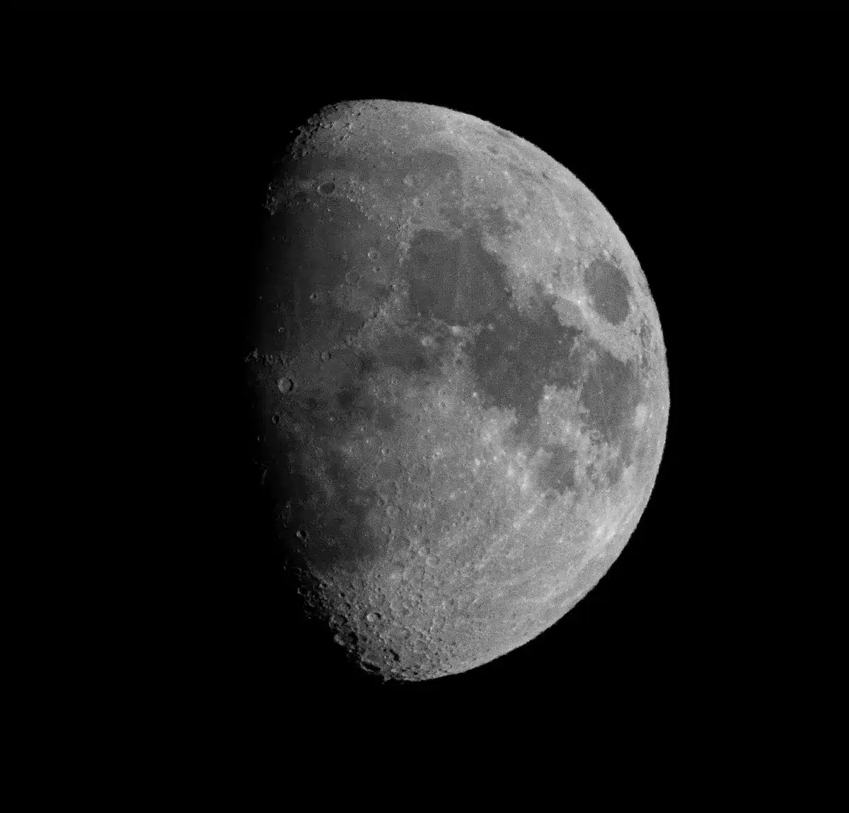 A lunar crater rim with fresh ejecta scattered across dark regolith, dust plume visible against the lunar horizon, impact site near Einstein Crater on the Moon's western limb.