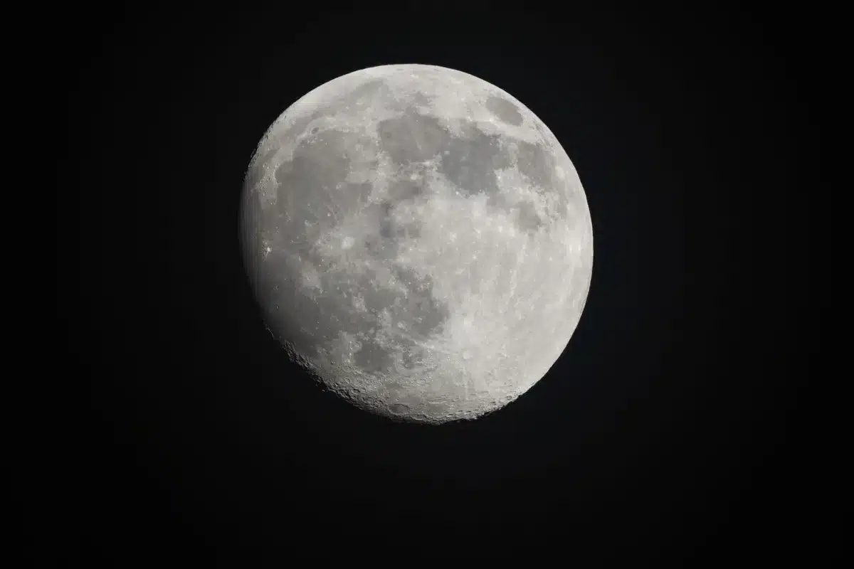 A telescope dome silhouetted against a star-filled sky, with the Moon visible in the frame, dust plume faintly illuminated near the lunar limb, observatory dome interior with equipment.