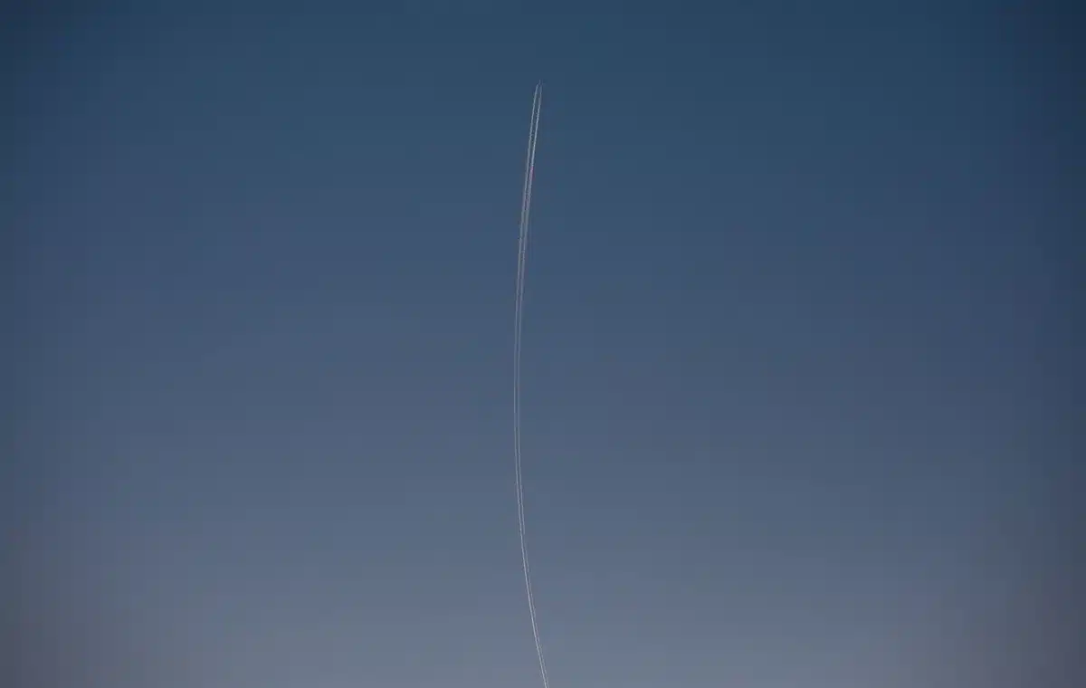 A Falcon 9 rocket on a launch pad at dawn, engines ready for ignition, with the Atlantic Ocean visible in the background and the pale morning sky above.