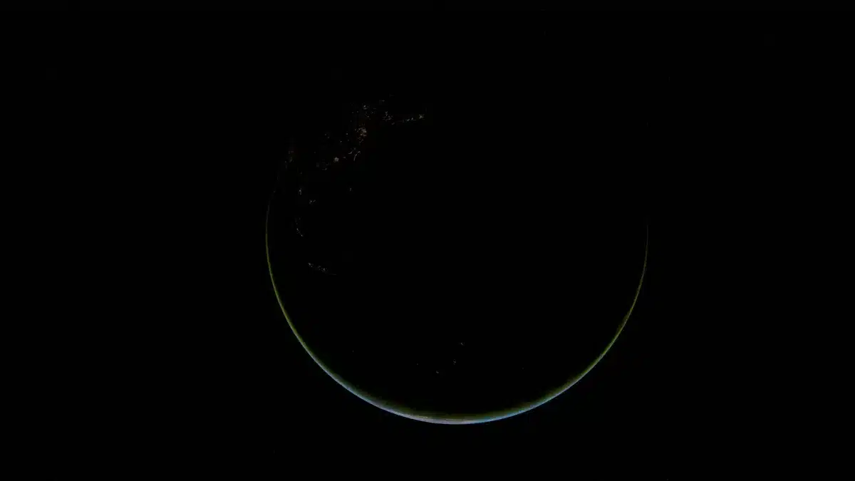 A split view of Earth from space: on one side, a dense cluster of bright satellite trails in low orbit representing the Starlink constellation; on the other, a sparse field of stars and the curve of Earth's atmosphere.