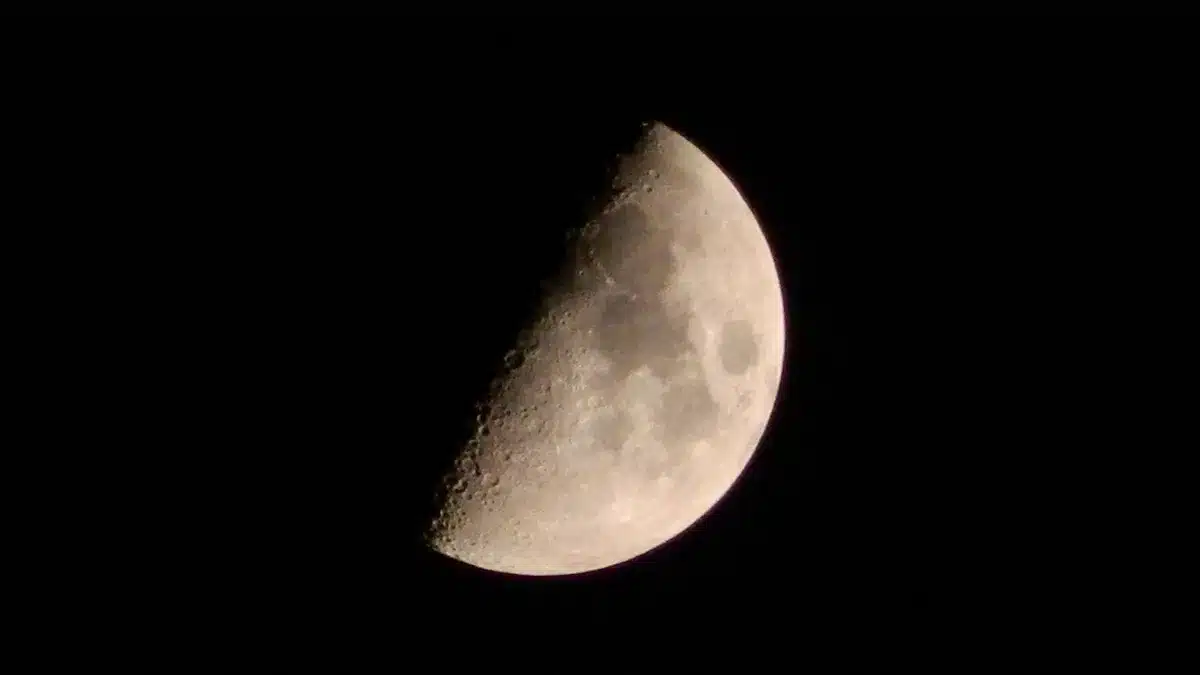A spent rocket stage hurtling toward a cratered lunar surface, approaching at extreme speed, the moon's surface growing larger in the frame, stark shadows and ancient craters visible, a moment of imminent impact.