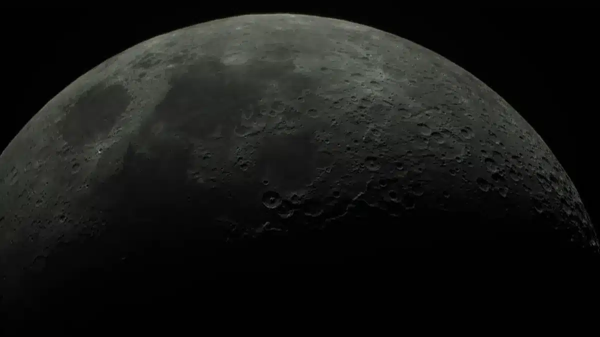A telescope pointing toward a starry night sky with the moon visible in the frame, control equipment and observation logs scattered nearby, an astronomer's hand adjusting focus mechanisms, anticipation evident in the setup.