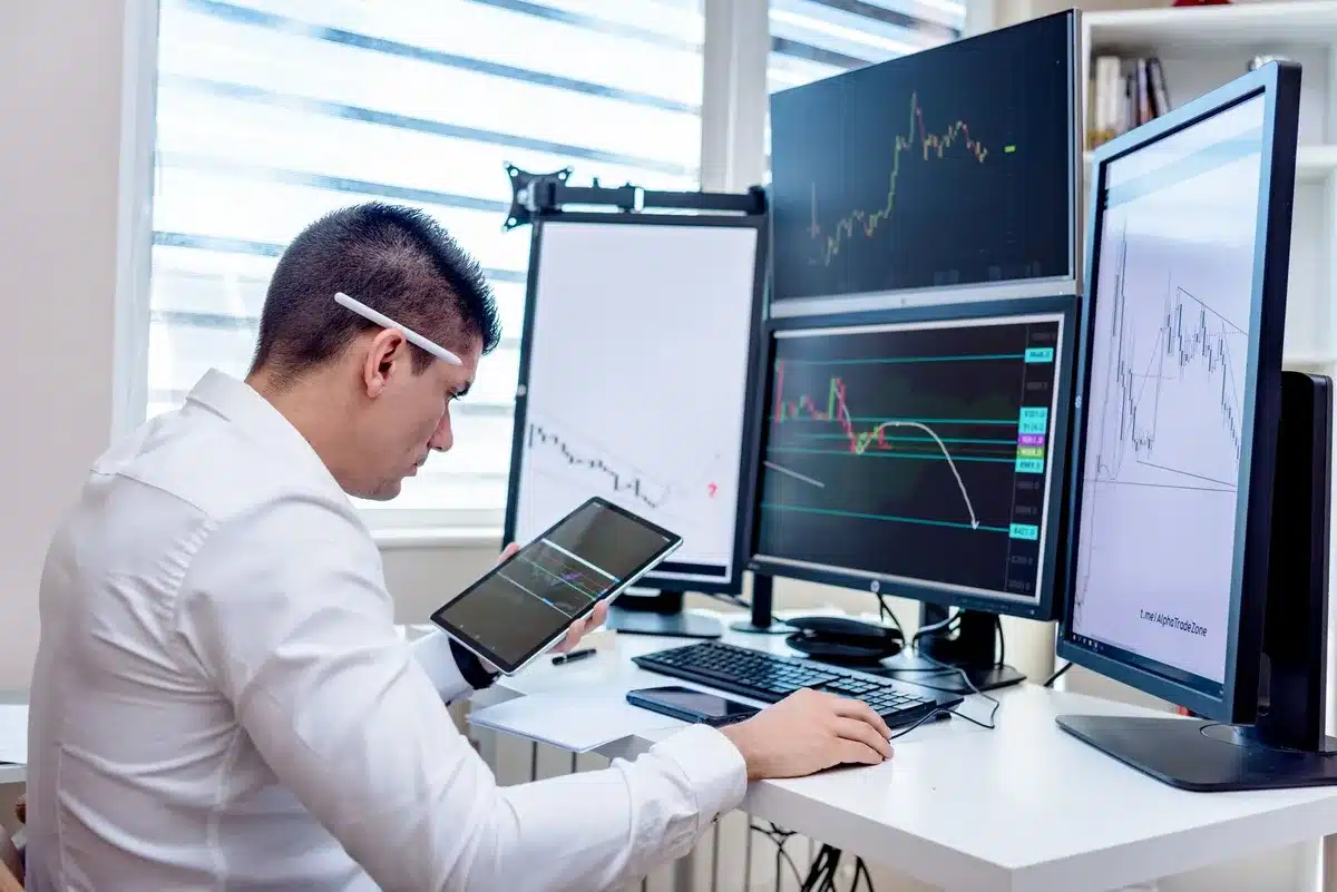 A stock market trading floor with glowing red and green price tickers, traders in motion blur reacting to sudden price movements, screens displaying sharp downward trending lines, tension and urgency in the air