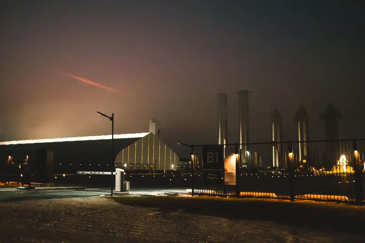A sleek rocket with multiple engines on its base rises vertically from a Texas launch pad at sunset, with billowing white exhaust clouds surrounding its lower stages and a clear sky above.