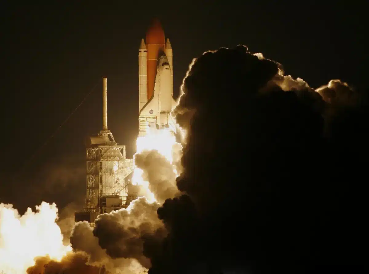 Towering launch pad with mechanical arms positioned at the top, a distant spacecraft descending under engine thrust, Texas desert landscape below, anticipation