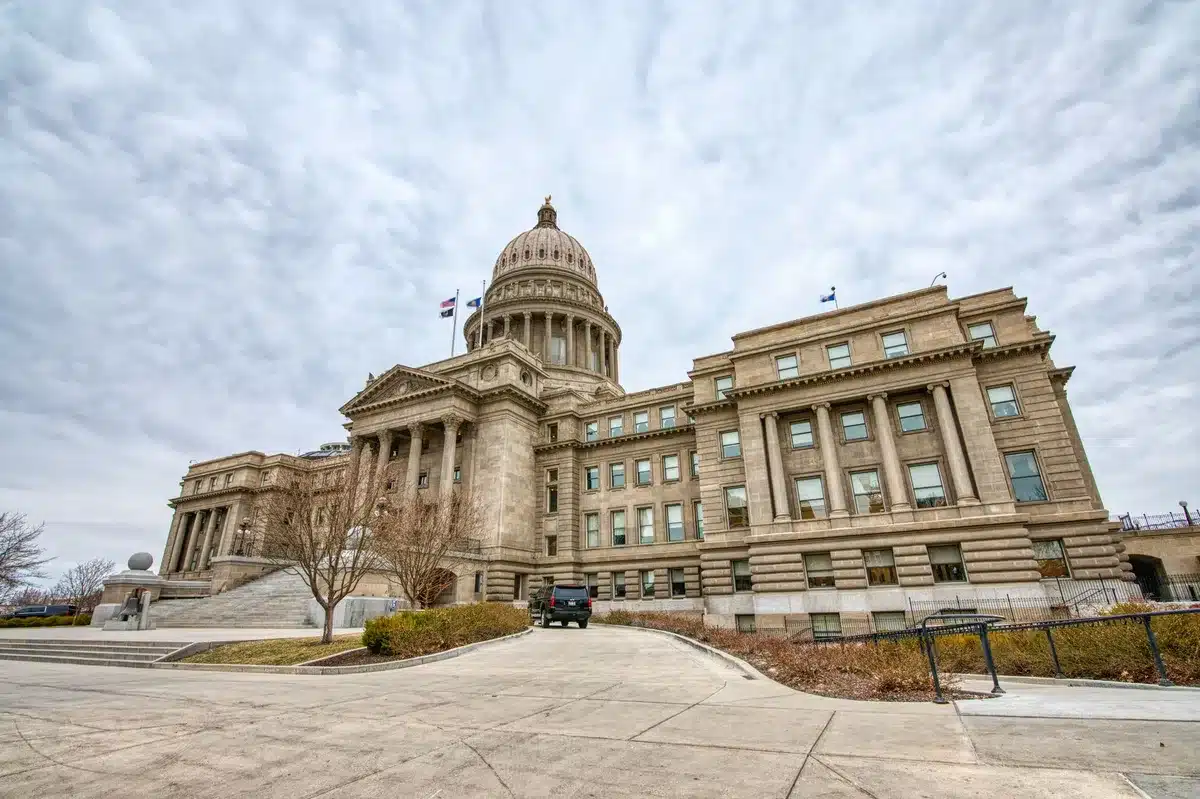A county courthouse or administrative building facade in afternoon light, with flags at the entrance and empty steps, representing local government and civic responsibility