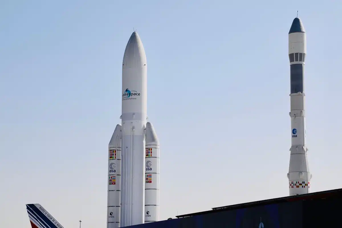 A massive booster standing vertical on a launch pad, all 33 engines glowing white-hot at the base, exhaust plumes billowing outward, the test structure surrounding the rocket backlit by the engine fire, capturing the moment of full-power ignition