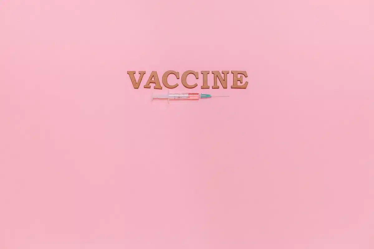 A stethoscope resting on an open medical reference guide showing vaccine schedules and immunization information, soft focus background