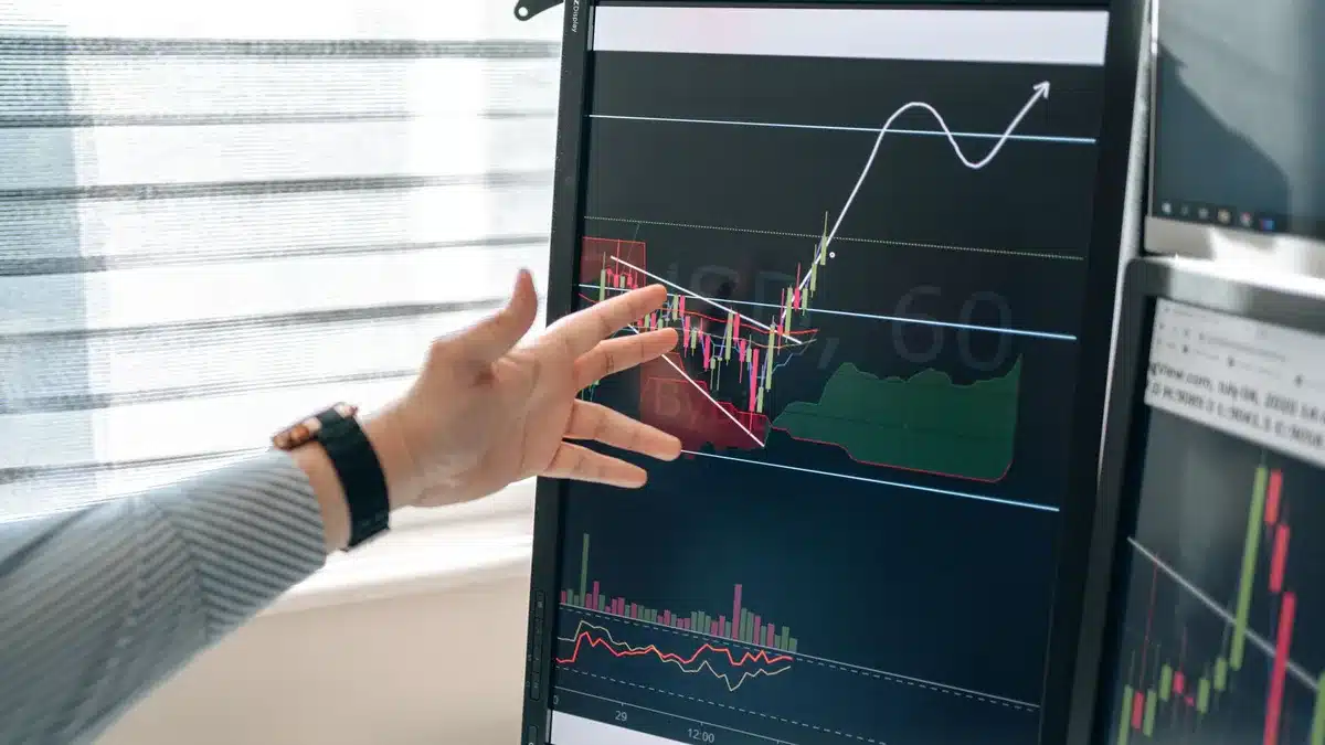 Stock market trading floor with multiple screens displaying green and red indices, traders monitoring earnings data, bright overhead lighting