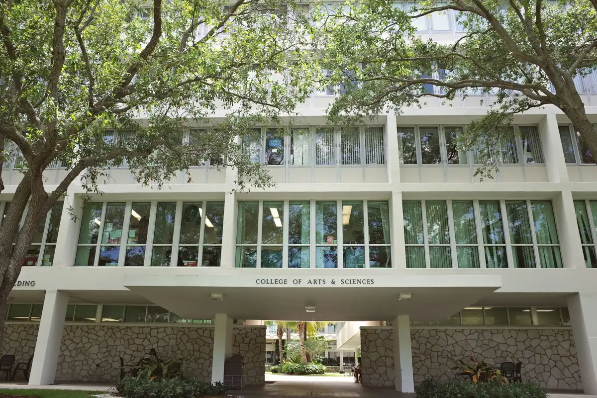 A college campus scene with students walking past a financial aid office building, symbolizing the new constraints on student borrowing and the start of the academic transition period.
