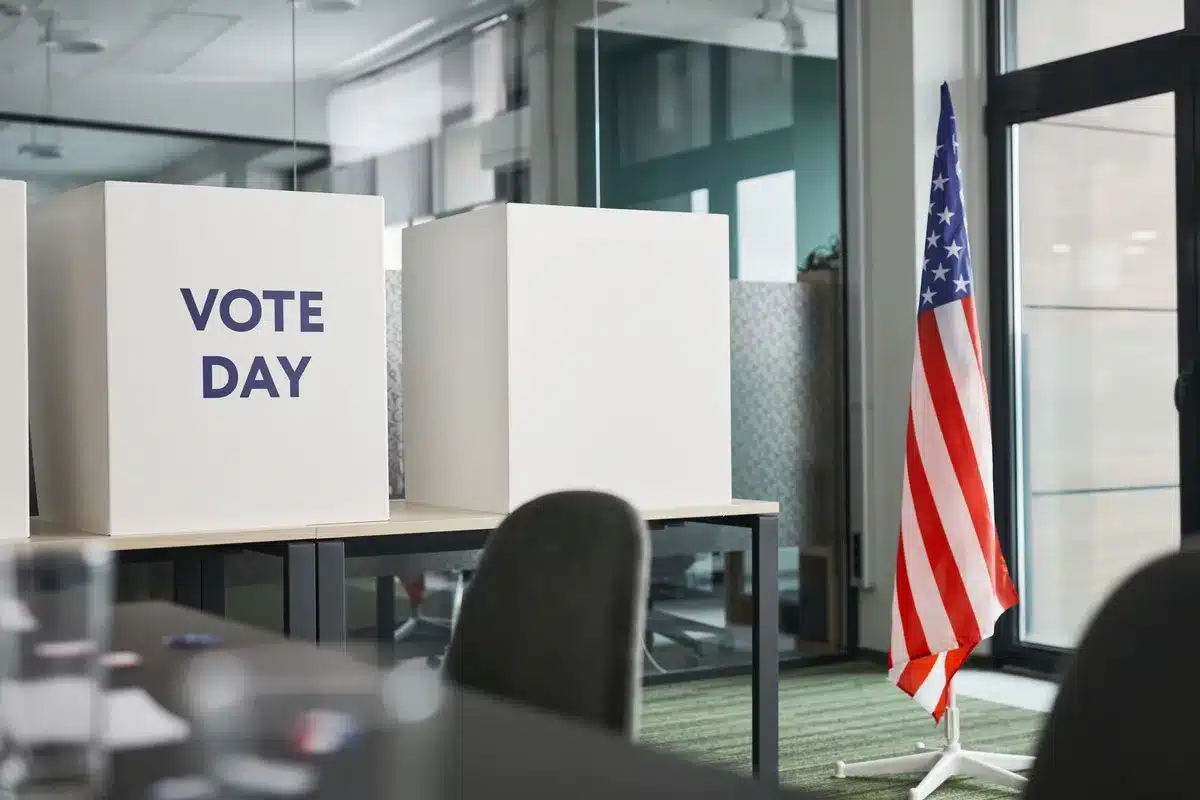 A crowded voting precinct with diverse voters filling out ballots at polling stations, election day atmosphere with American flags visible