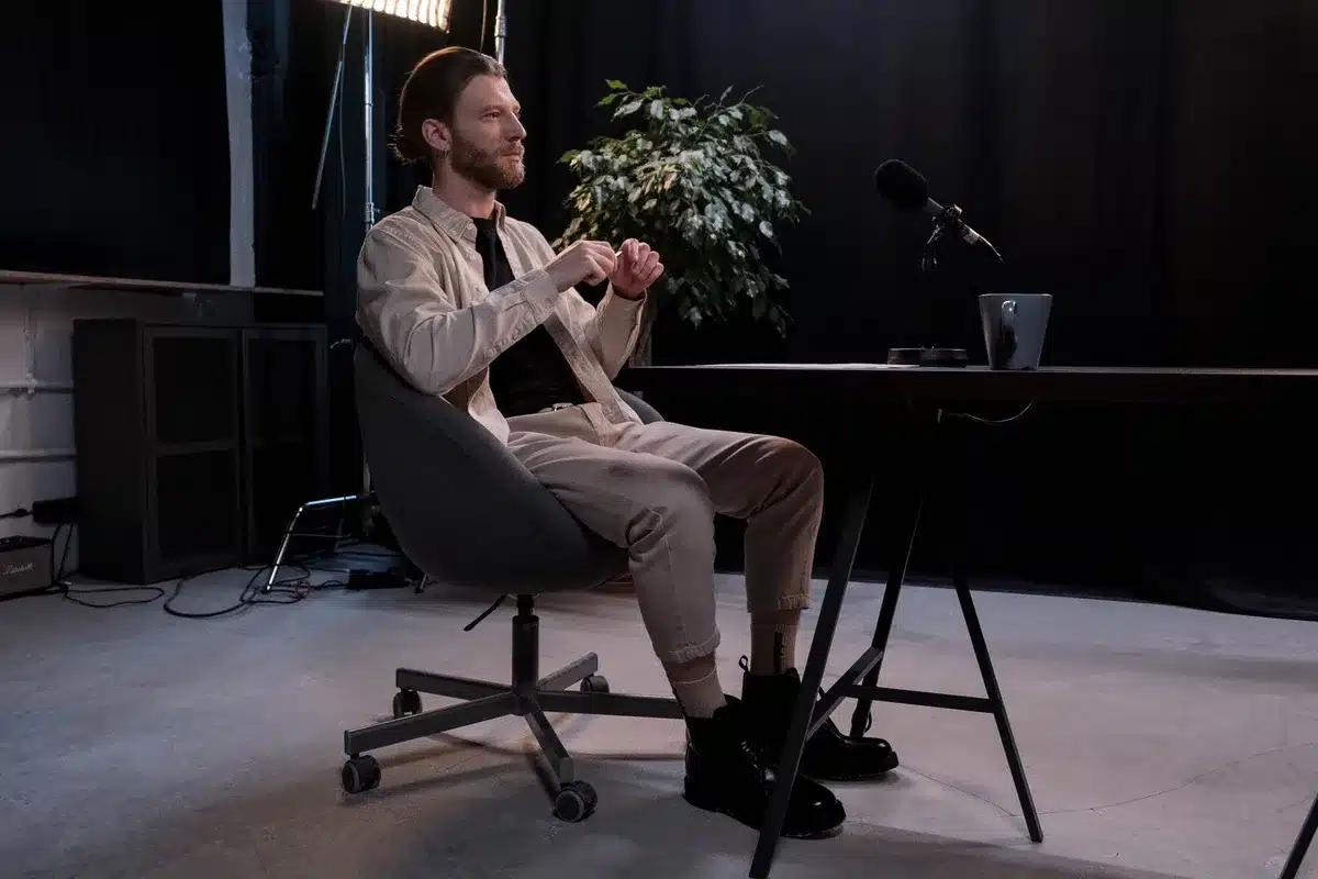 A conservative justice seated in a studio setting with microphones visible, warm lighting on a podium, a leather chair in soft focus, suggesting a podcast or interview environment.