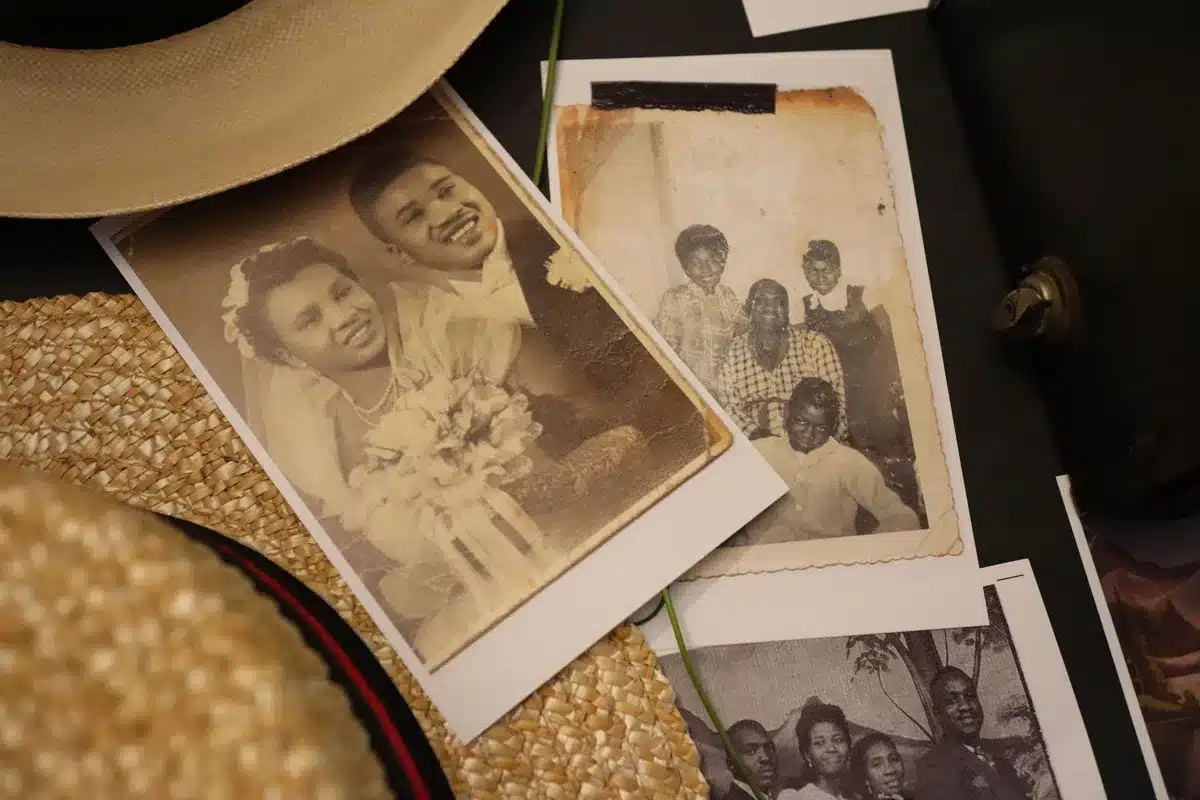 A worn photograph or memoir displayed on a simple wooden surface, dust particles visible in soft light, suggesting reflection on legacy and family history.