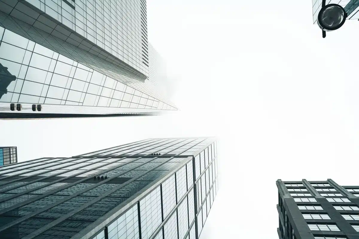 A modern glass building exterior with blurred financial charts visible through windows, representing corporate investment structures.